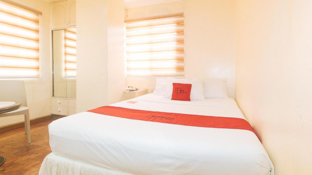 um quarto com uma cama branca e uma almofada vermelha em RedDoorz @ Tondaligan Beach Hotel em Dagupan
