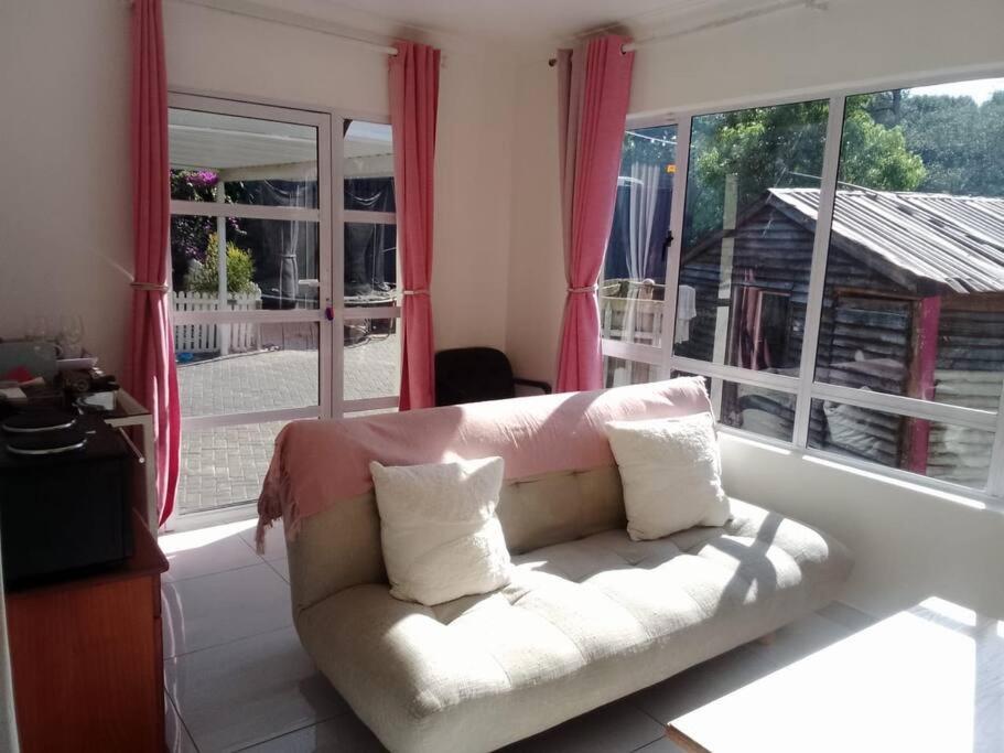a living room with a white couch in front of a window at Bright and Sunny Studio Cottage in Durban