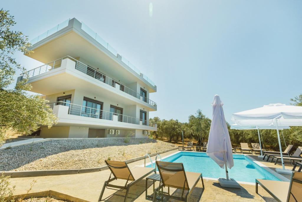 a villa with a swimming pool with chairs and an umbrella at La Perla Del Campo in Kánalos