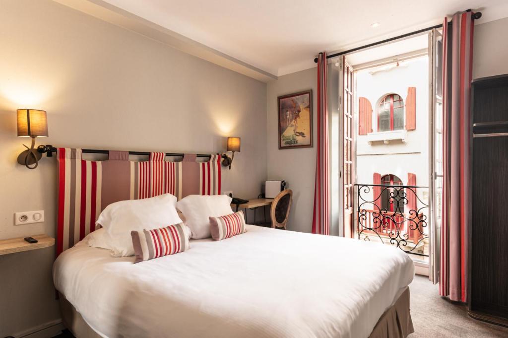 a bedroom with a large bed with red and white pillows at Boutique H&ocirc;tel Txoko in Saint-Jean-de-Luz