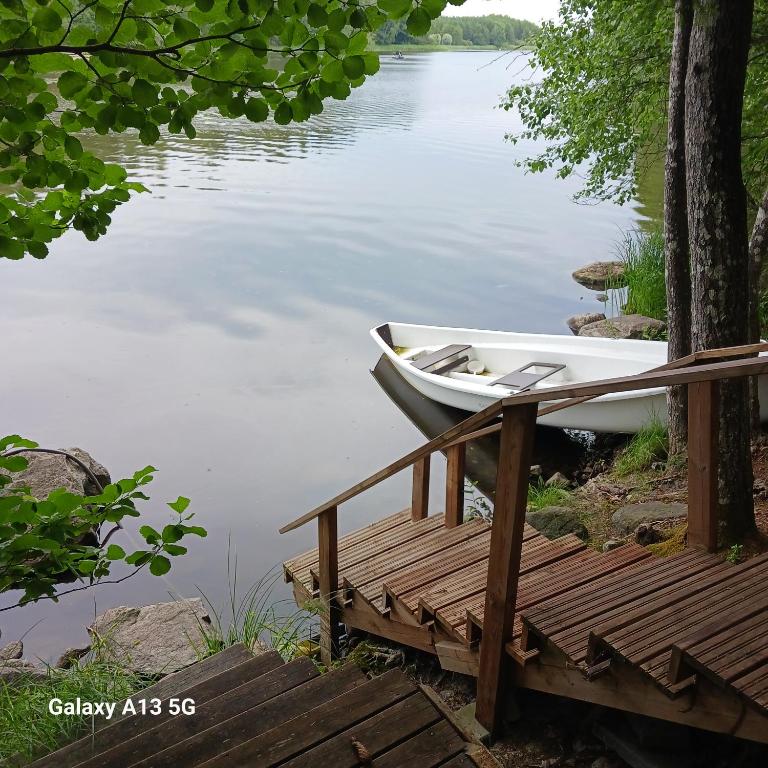 a boat sitting on the water next to a dock at Cottage / Mökki, unique summer cottage in Vihti