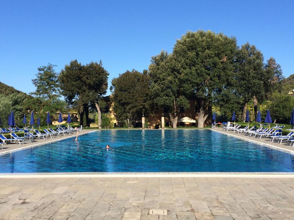 a pool with chairs and a person swimming in it at Sant'Anna Del Volterraio - Papaveri 7 in SantʼAnna
