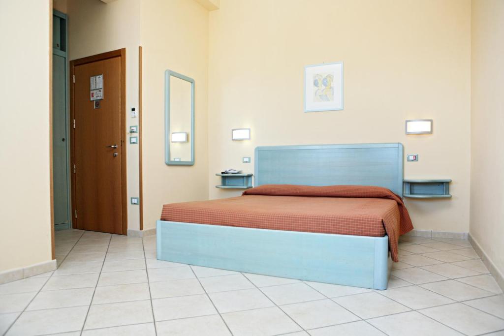 a bedroom with a bed with a orange blanket at Abbazia Club Hotel Marotta in Marotta