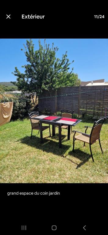 une table de pique-nique et deux bancs dans l'herbe dans l'établissement Rez de villa avec jardin, à Porto-Vecchio