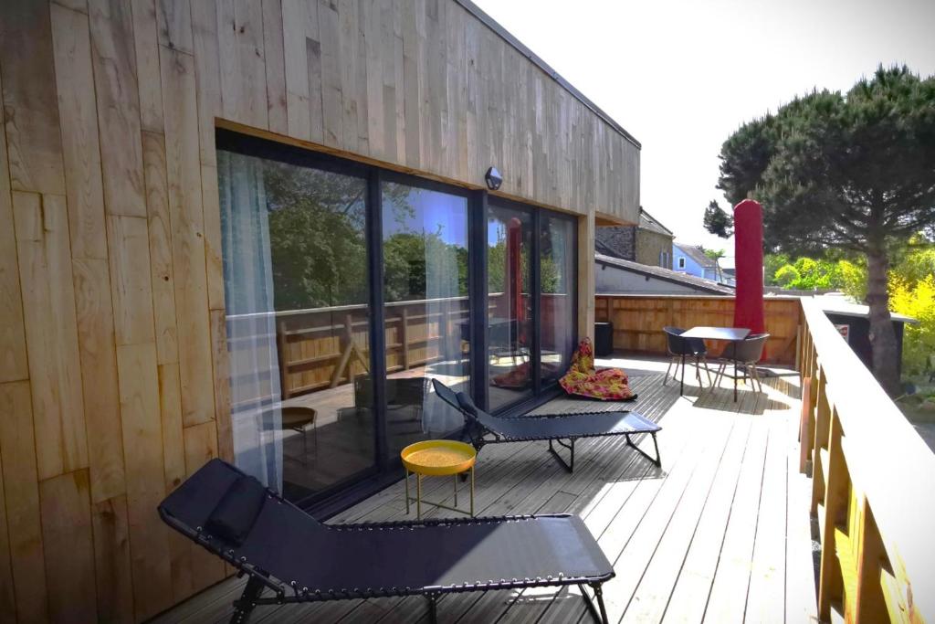 a deck with chairs and tables on a building at Appartement dans maison d'architecte avec terrasse in Saint-Lunaire