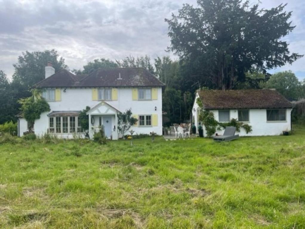 ein großes weißes Haus auf einem Grasfeld in der Unterkunft Thimble Cottage in Buckinghamshire