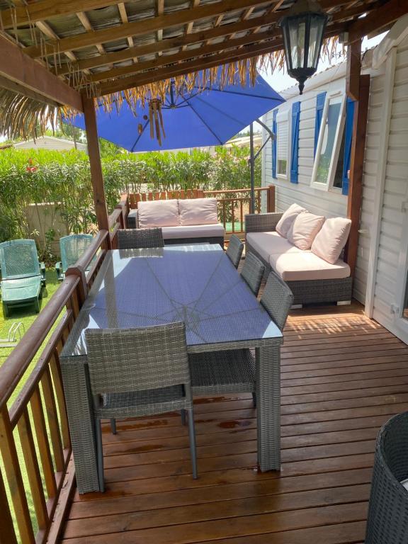 un patio avec une table, des chaises et un parasol dans l'établissement Mobil Home dans le camping 4 étoiles le Montourey, à Fréjus