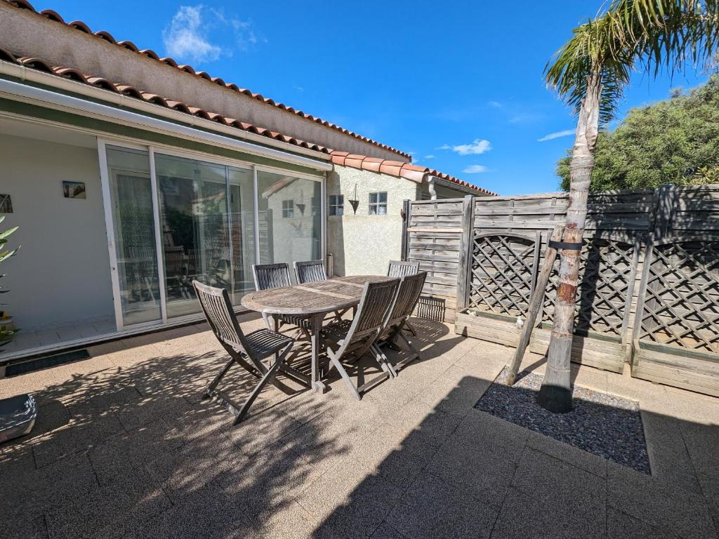 une table et des chaises sur une terrasse avec un palmier dans l'établissement Villa T3 Spacieuse à Port-la-Nouvelle – Jardin, Parking, à 900m de la Plage, Chien Admis - FR-1-797-50, à Port-la-Nouvelle