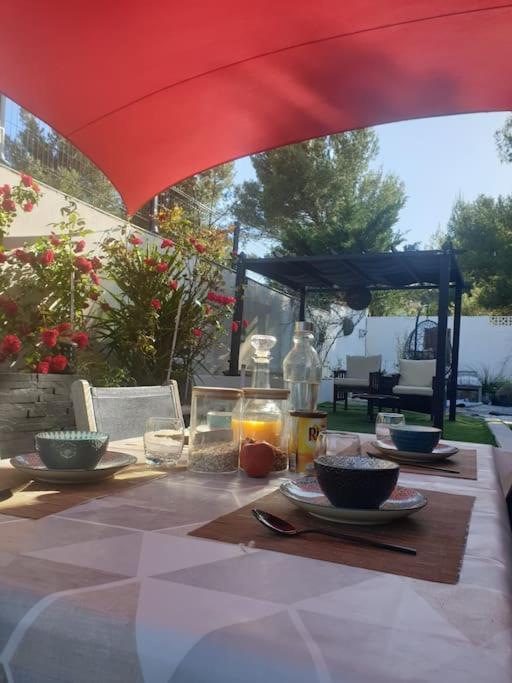 une table avec des bols de nourriture sur une table sous un parasol dans l'établissement Jolie villa avec un bel extérieur exposition Sud, à Pézenas
