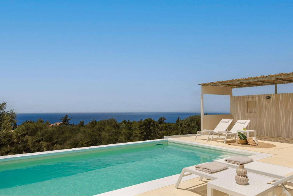una piscina con due sedie a sdraio e l'oceano di Villa Elena - Zen Villas a Fiskardho