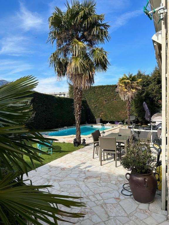 un patio avec une table et des chaises à côté d'une piscine dans l'établissement Super appartement douillet dans maison, à Seyssins