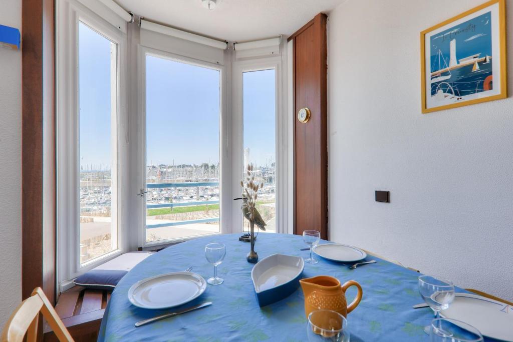 Un comedor con una mesa azul con vista a la playa. en Vue sur le port du Crouesty, appartement pour 5, en Arzon