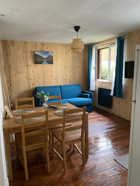 a living room with a table and a blue couch at Studio chaleureux rénové in Allemont