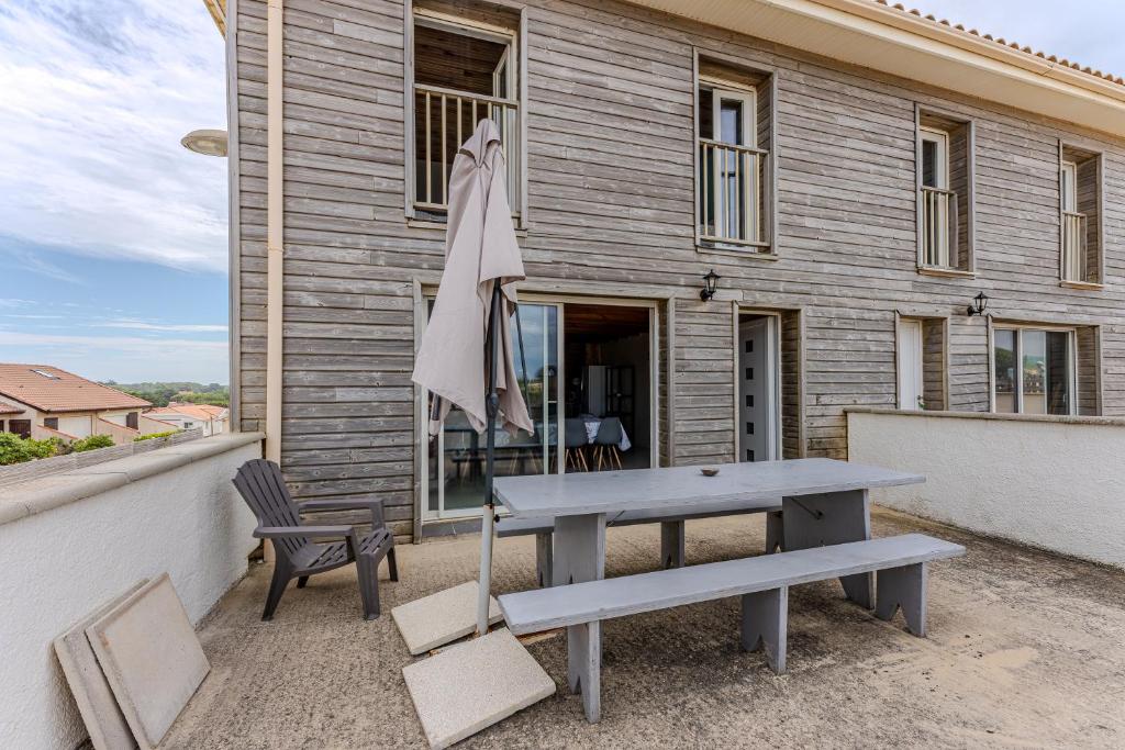 ミミザンにあるMaison Bord De L'Océan 3 étoilesのバルコニーにピクニックテーブルと椅子と傘