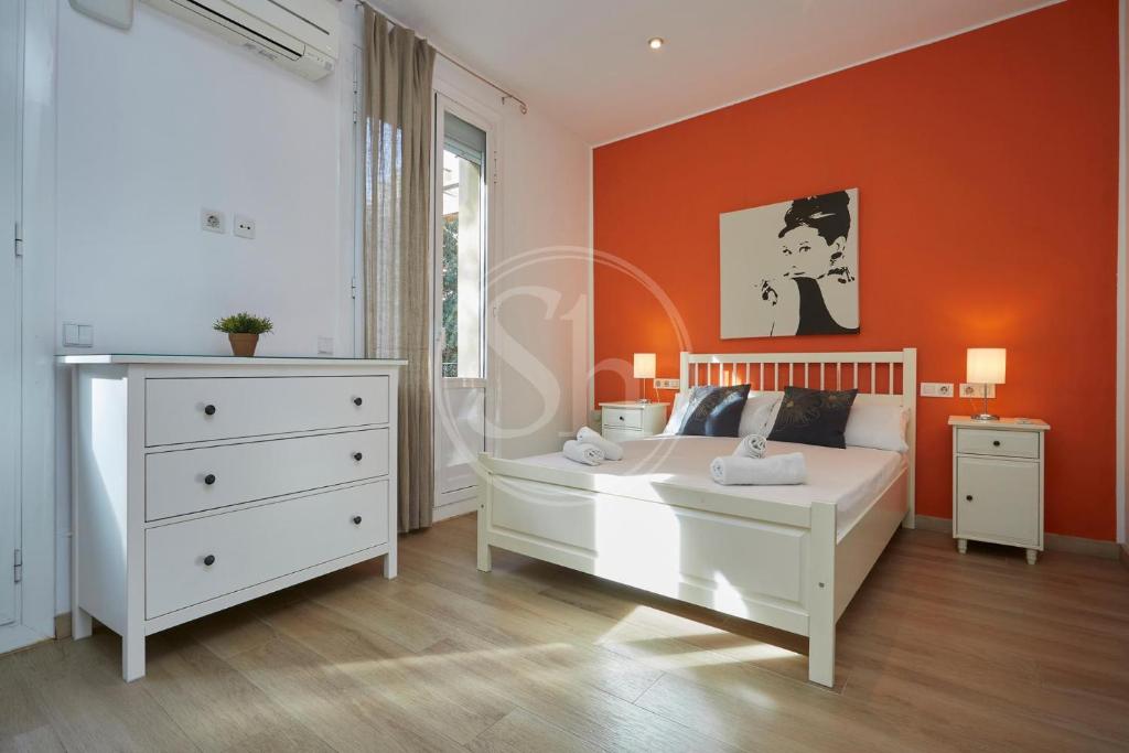a bedroom with a white bed and an orange wall at Bonito apartamento cerca de Plaza España in Barcelona