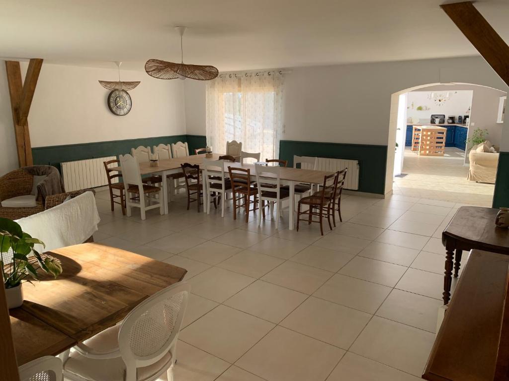 a dining room with tables and chairs and a clock on the wall at Gite de Groupe Aux Instants Partagés in Fontenay-sur-Vègre