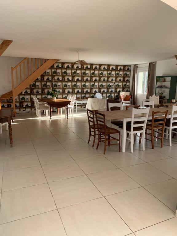 a dining room with tables and chairs in a library at Gite de Groupe Aux Instants Partagés in Fontenay-sur-Vègre