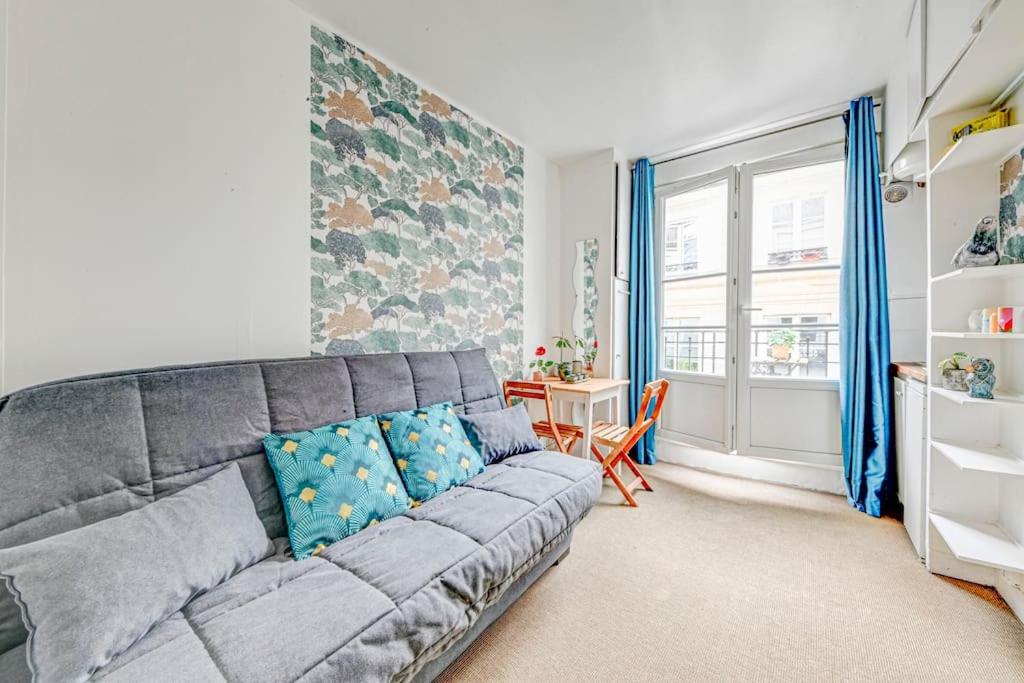 un salon avec un canapé gris et une table dans l'établissement Petit studio cosy à Saint-Germain-Des-Prés et Jardin du Luxembourg, à Paris