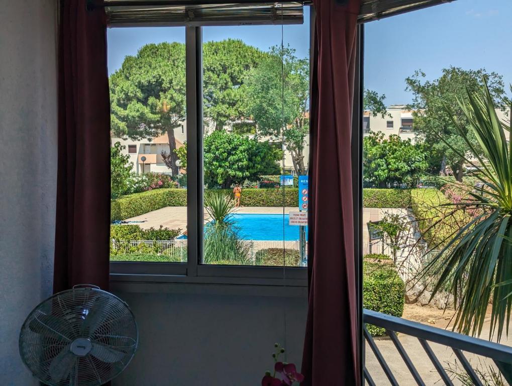- une fenêtre offrant une vue sur la piscine depuis une maison dans l'établissement Sol-y-Days Caraïbes piscine collective à deux pas des plages, au Grau-du-Roi
