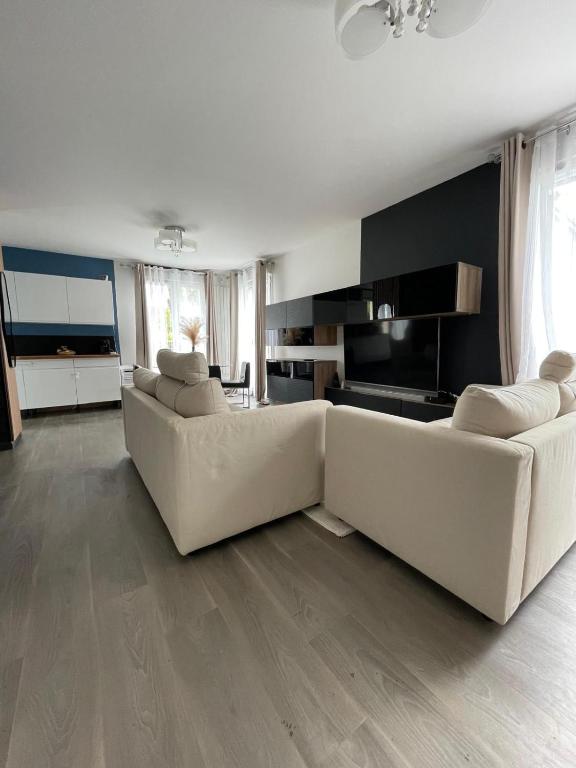 un salon avec deux canapés blancs et une cuisine dans l'établissement Charmante Maison Piscine Privée, à Vert-Saint-Denis