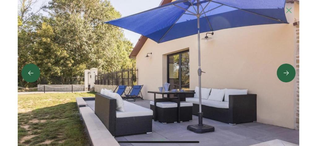 a blue umbrella sitting on top of a patio at Gite de groupe La Laiterie in Banneville-la-Campagne