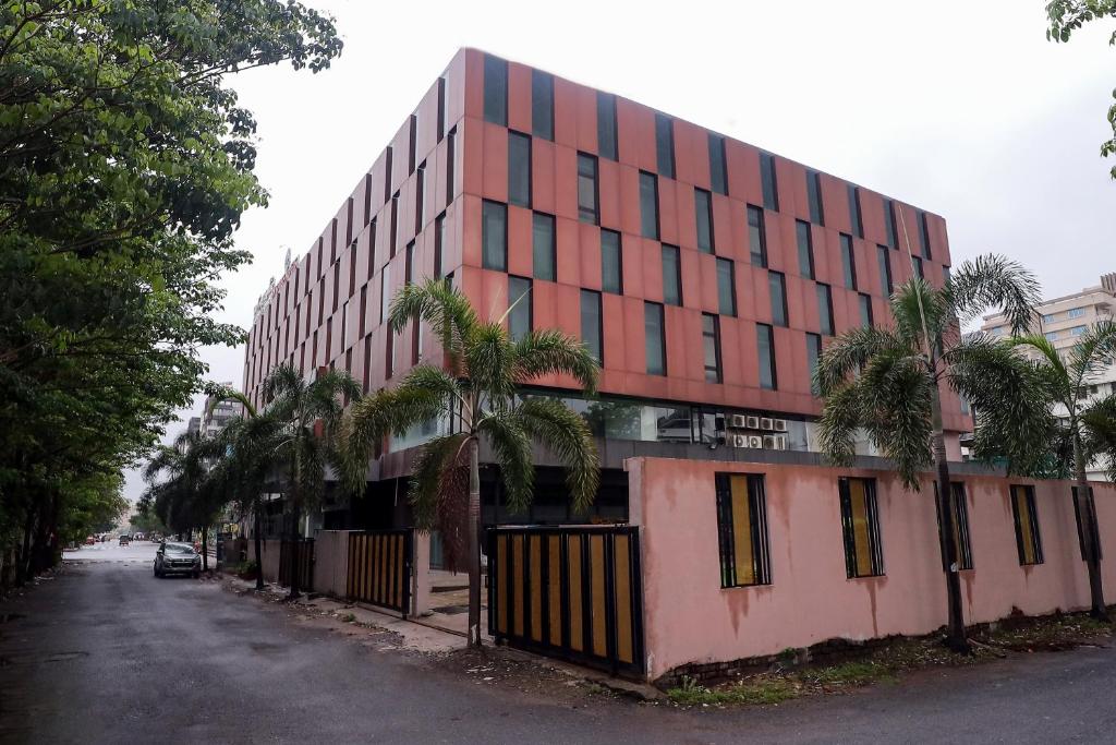 a red building with palm trees in front of a street at Zip By Spree Hotels Surat in Surat