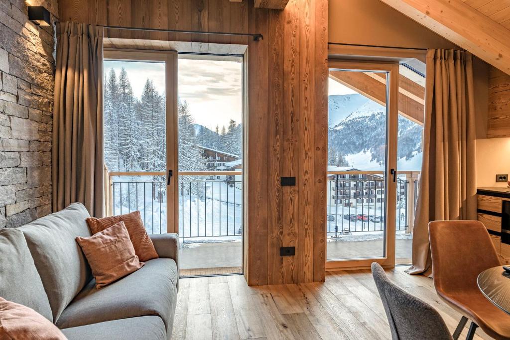 a living room with a couch and a large window at LIVIN JOY Bivio Travel in Livigno