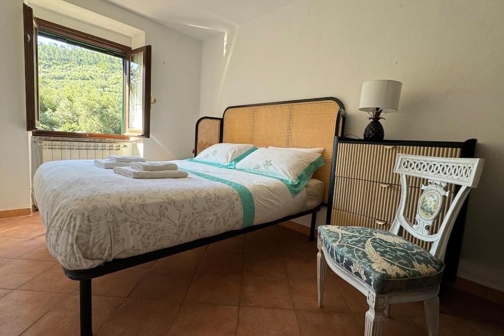a bedroom with a bed and a chair and a window at Cinque Terre - House & Garden Paradise in Volastra
