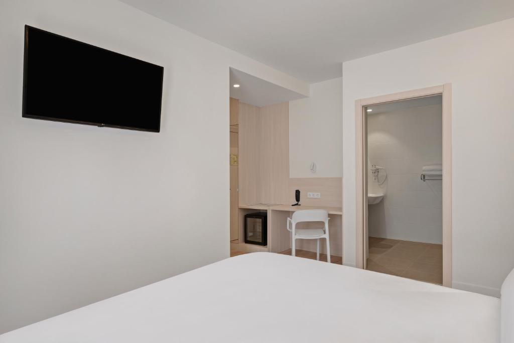 a bedroom with a white bed and a flat screen tv at B&B HOTEL Santiago Milladoiro in Milladoiro