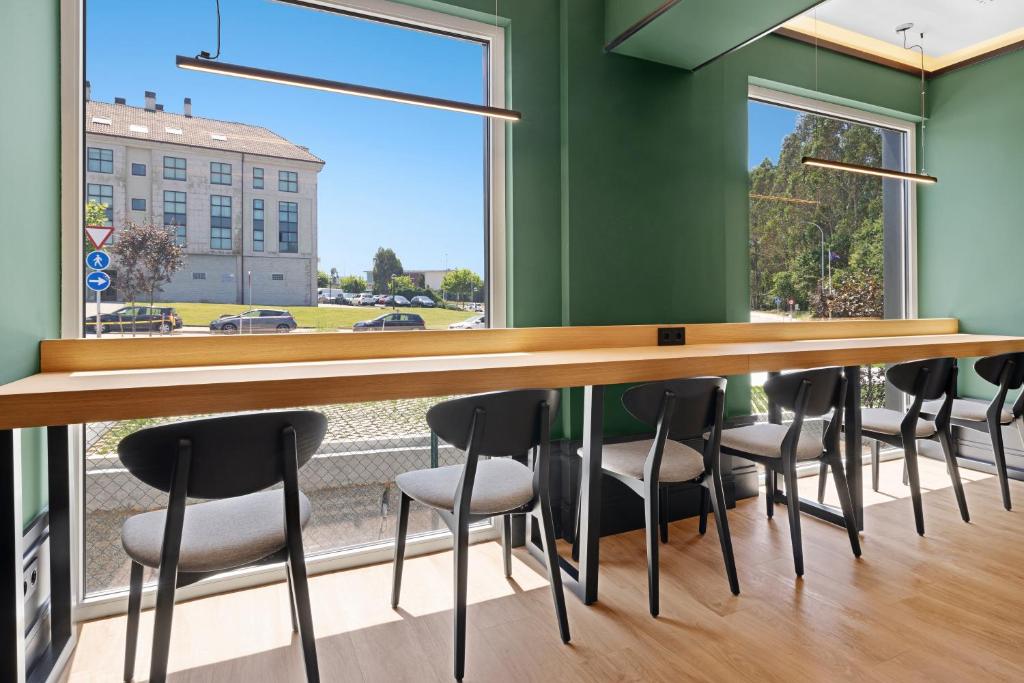 a row of tables and chairs in a room with a large window at B&B HOTEL Santiago Milladoiro in Milladoiro