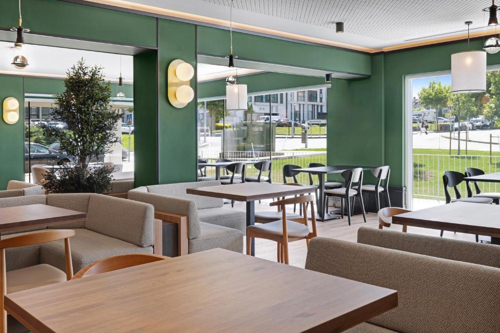 a restaurant with tables and chairs and windows at B&B HOTEL Santiago Milladoiro in Milladoiro