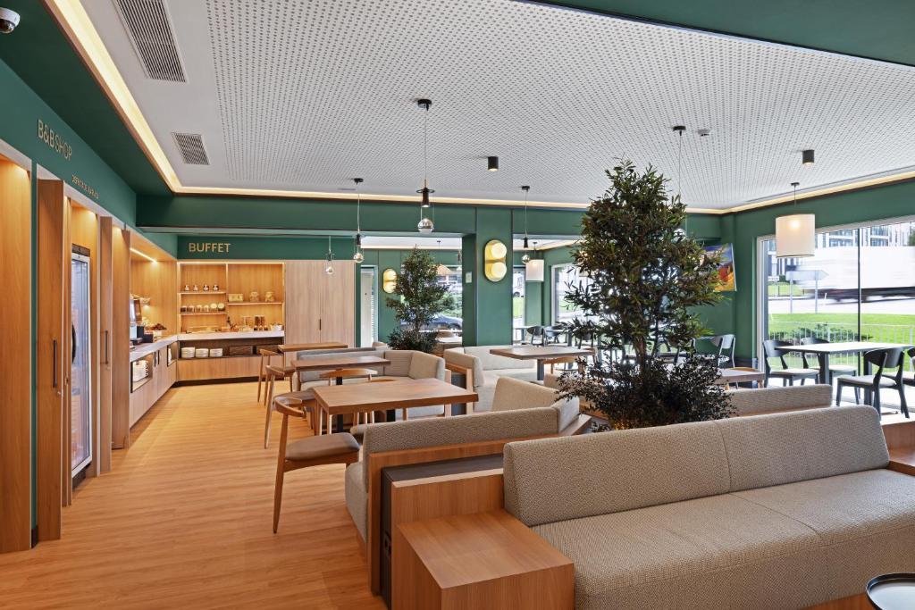 a lobby with couches and tables in a cafeteria at B&B HOTEL Santiago Milladoiro in Milladoiro