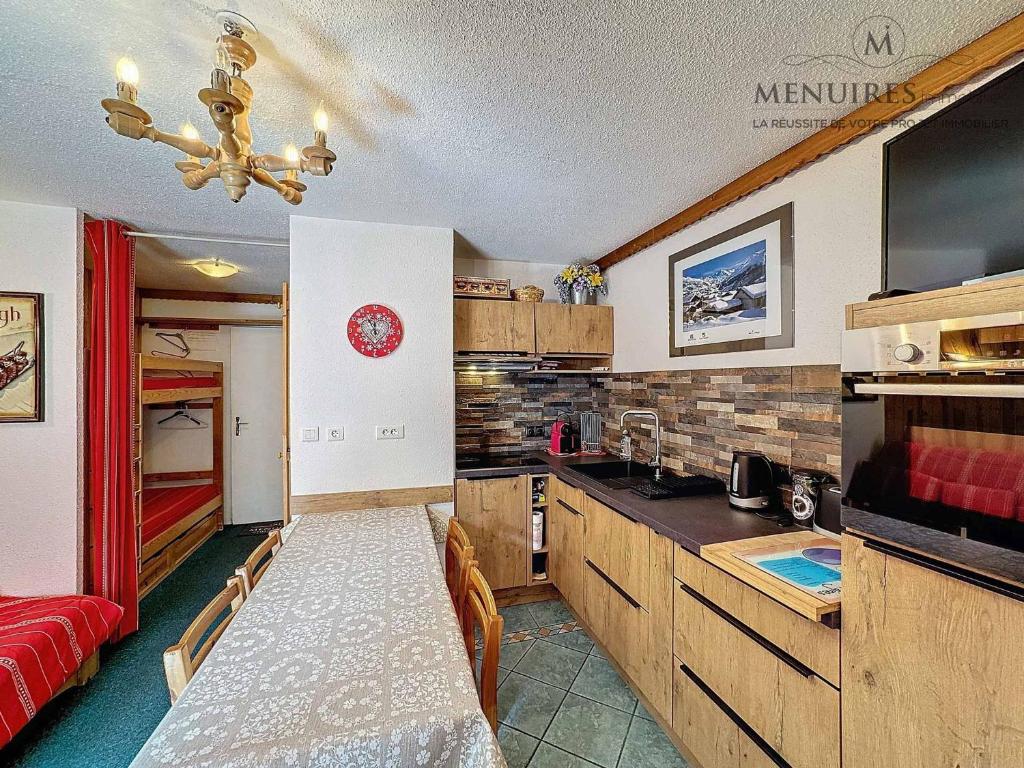 une cuisine avec une table et un canapé rouge dans l'établissement Les Bruyères - 2 pièces 4 pers. - Ski aux pieds, balcon, emplacement idéal, proche commerces - FR-1-178-99, aux Menuires