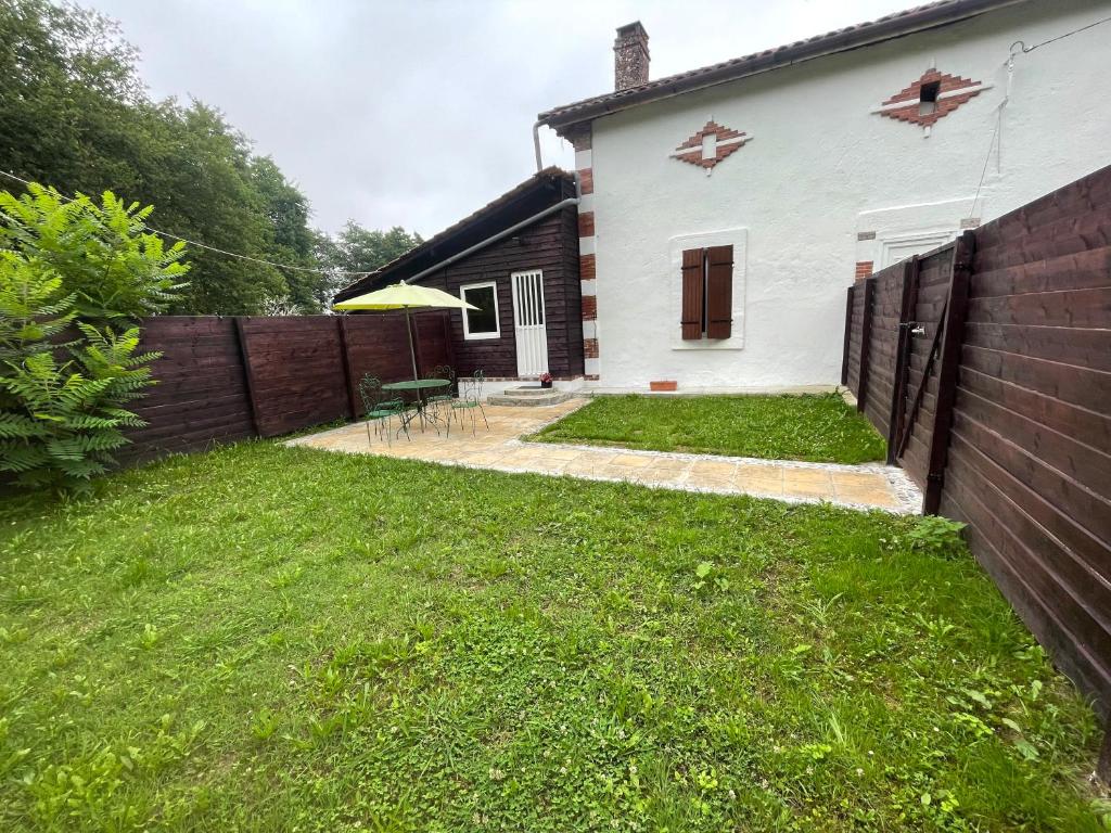 une arrière-cour avec une maison blanche et une clôture dans l'établissement Jouandilla, à Mazerolles