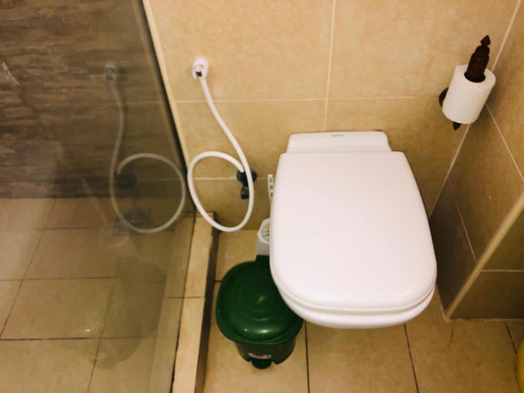 a bathroom with a toilet and a green trash can at Harmony Homes Beachfront in Diani Beach