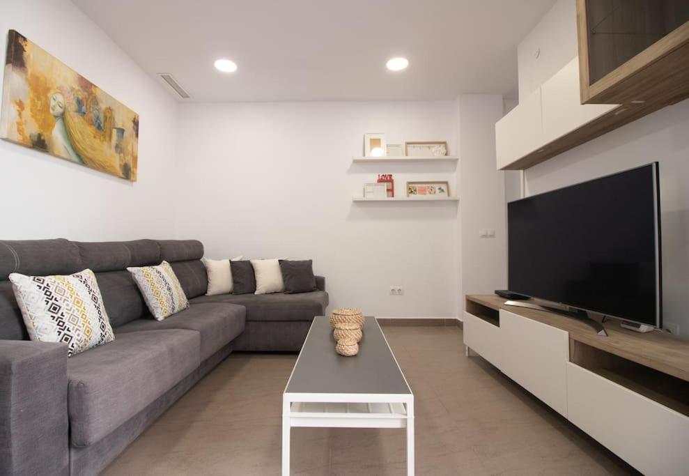 Una sala de estar con un sofá y un televisor. en Malasaña House, en Málaga