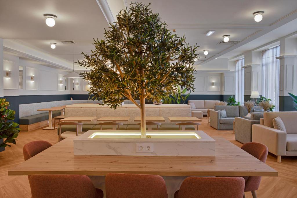 a table with a tree in the middle of a room at B&B HOTEL Figueira Da Foz in Figueira da Foz
