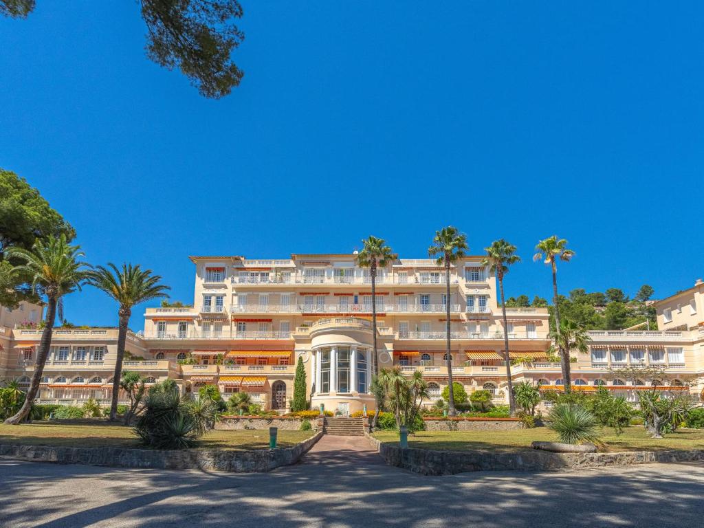 un grand bâtiment avec des palmiers devant dans l'établissement Apartment Mont des Oiseaux-3 by Interhome, à Hyères
