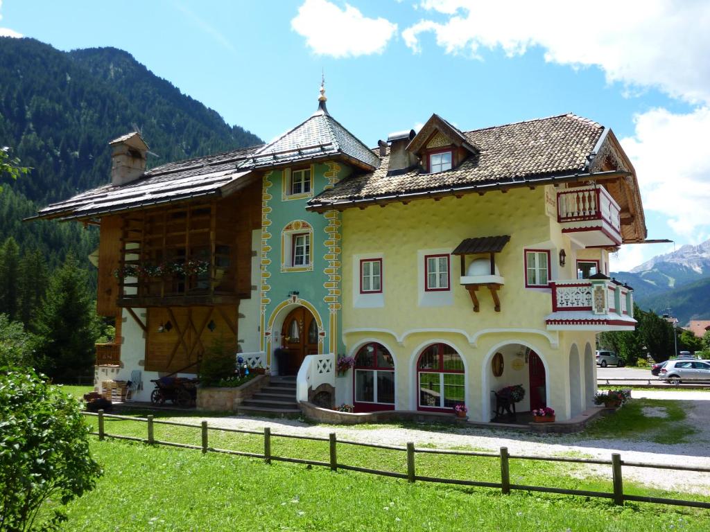 a house in the mountains with a fence at Appartamenti Majon Sotroi in Campitello di Fassa