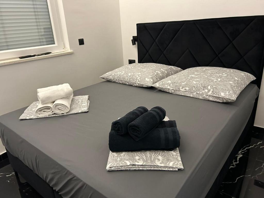 1 cama con 2 almohadas y toallas en Emma, en Bar