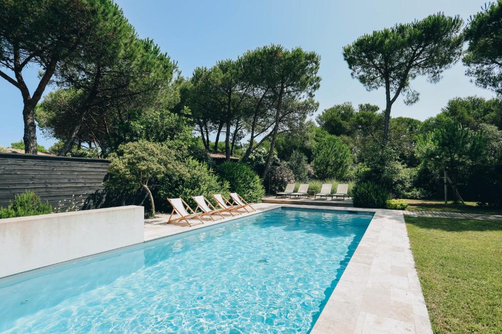 - une piscine avec des chaises et des arbres dans une cour dans l'établissement Villa du Fier, aux Portes