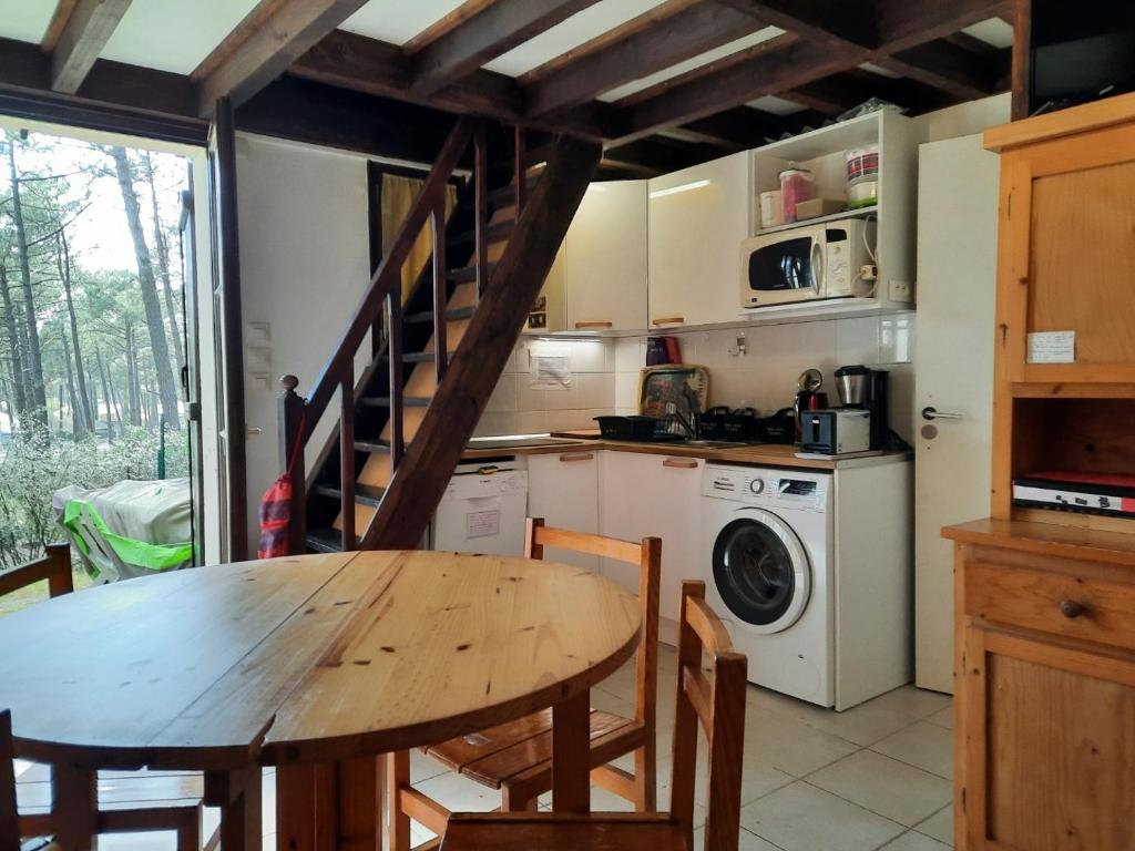une cuisine avec une table en bois et un lave-linge dans l'établissement PROMO Maisonnette donnant sur la Pinède, à Lacanau-Océan