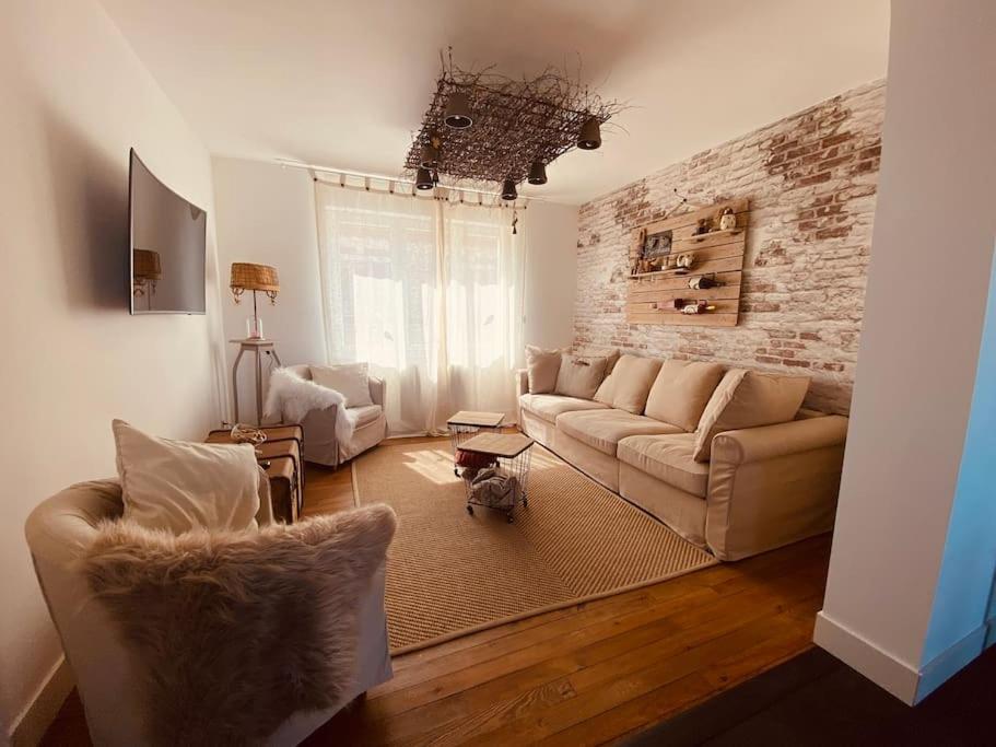 un salon avec un canapé et un mur de briques dans l'établissement L heurt du R Épi, à Le Portel
