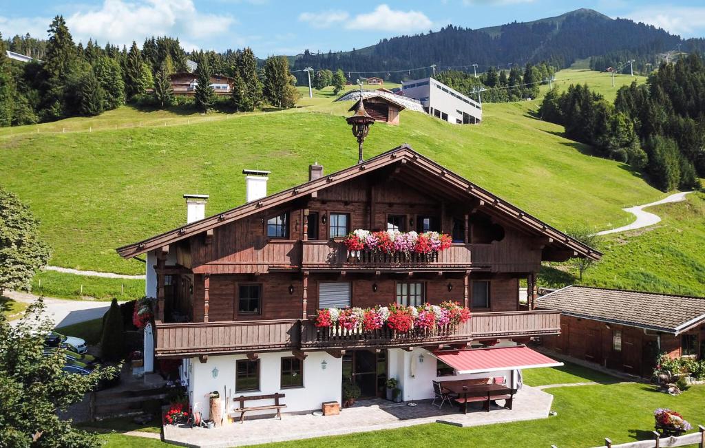 a house with flowers on a balcony on a hill at Ferienwohnung Mit Bergpanorama in Hopfgarten im Brixental