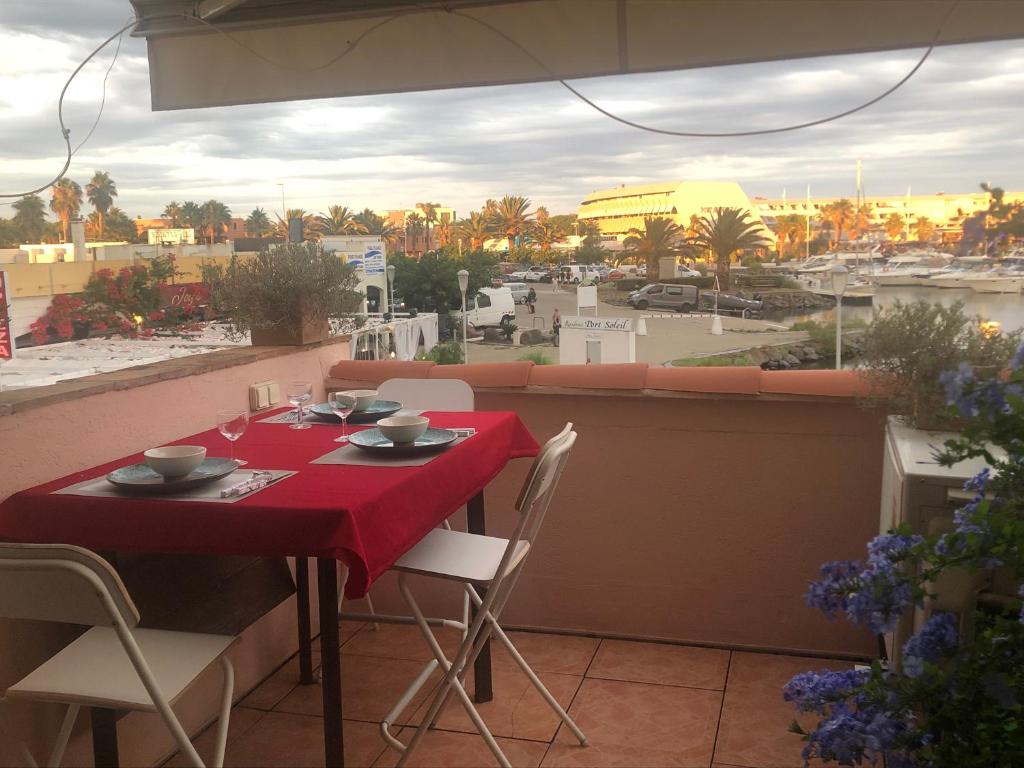 une table avec un chiffon rouge sur un balcon dans l'établissement Votre espace glamour EN COHABITATION avec nous deux dans notre appartement du village naturiste, au Cap d'Agde