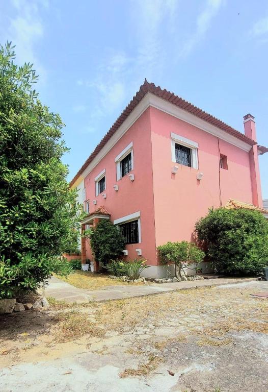 a pink house with a tree in front of it at A Casa do Escritor in Vila do Conde