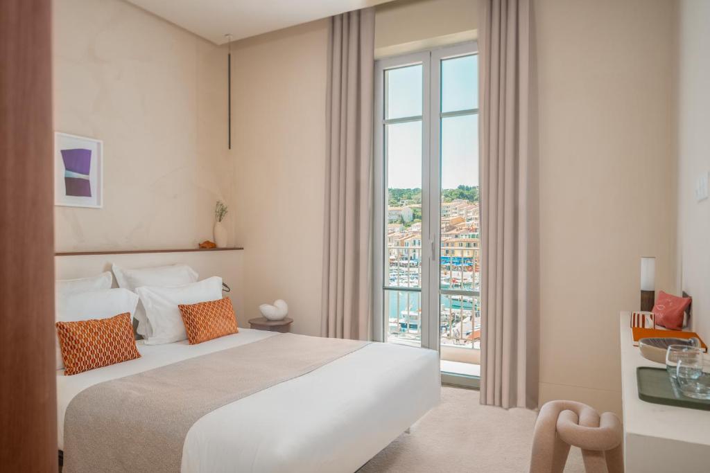 a hotel room with a bed and a large window at Hôtel Liautaud Rooftop Cassis in Cassis