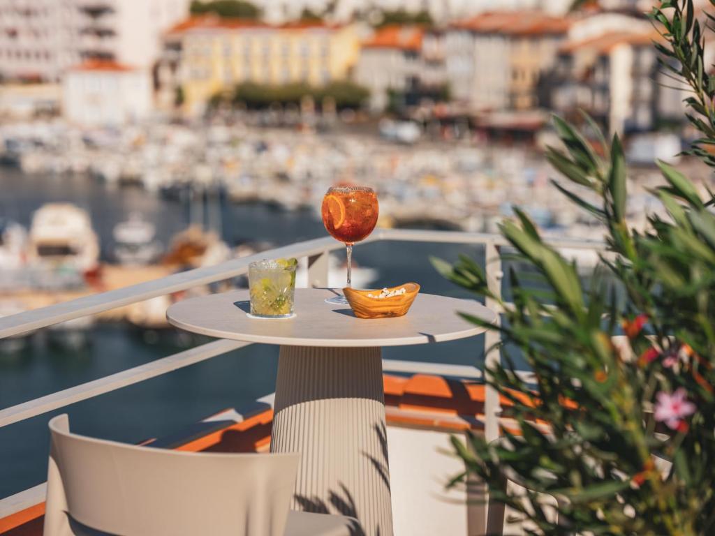 a table with a glass of wine on a balcony at Hôtel Liautaud Rooftop Cassis in Cassis