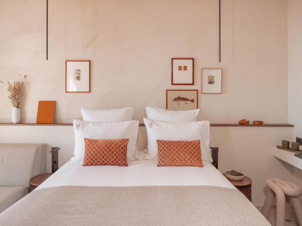 a bedroom with a white bed with orange pillows at Hôtel Liautaud Rooftop Cassis in Cassis