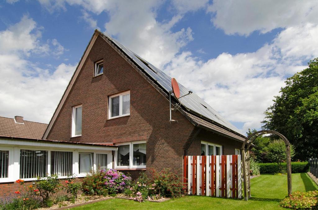 a brown brick house with a solar roof at Ferienhaus Gerda Wohnung 1 in Westochtersum